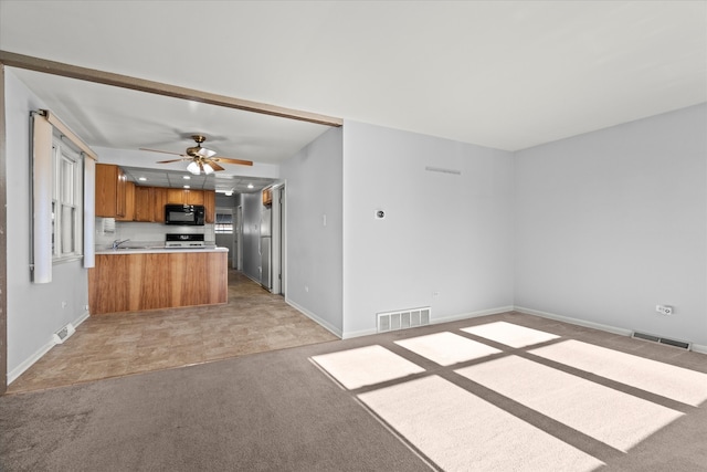 kitchen featuring ceiling fan, sink, kitchen peninsula, stove, and light colored carpet