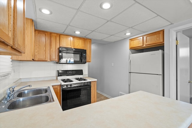 kitchen featuring kitchen peninsula, backsplash, a paneled ceiling, white appliances, and sink