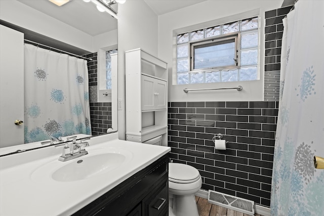 bathroom featuring hardwood / wood-style floors, vanity, toilet, and tile walls