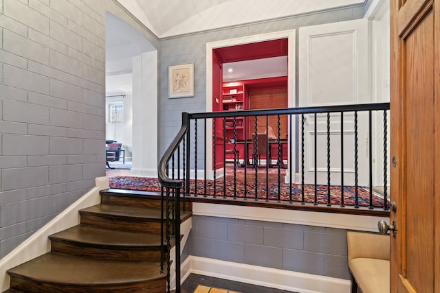 staircase with tile walls and lofted ceiling