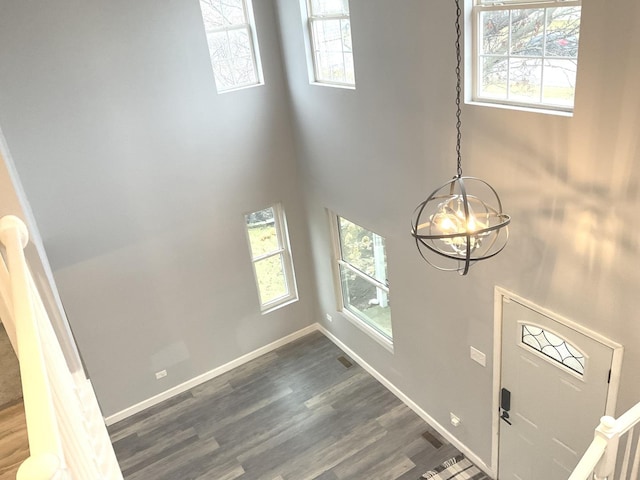 entrance foyer featuring a towering ceiling, dark hardwood / wood-style floors, and a notable chandelier