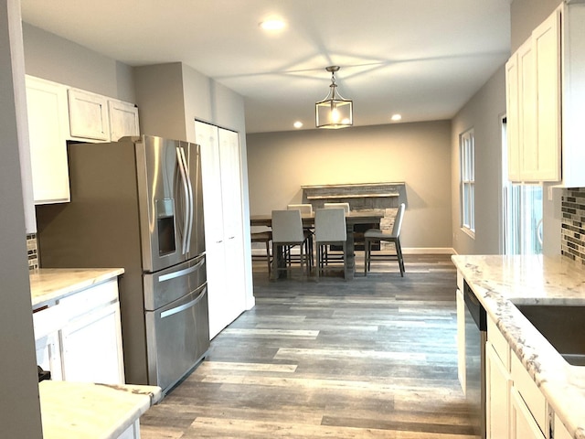 kitchen with light stone countertops, backsplash, stainless steel appliances, pendant lighting, and white cabinetry