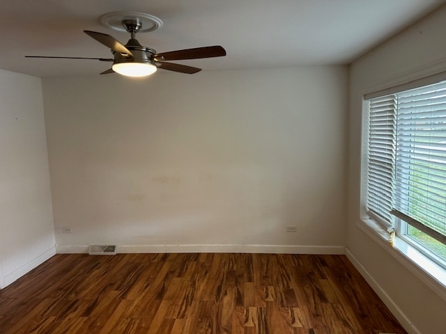 empty room with ceiling fan and dark hardwood / wood-style flooring