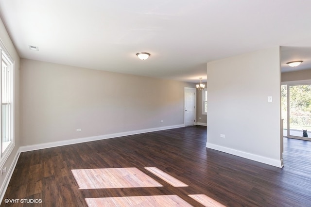 spare room with dark hardwood / wood-style flooring and a chandelier