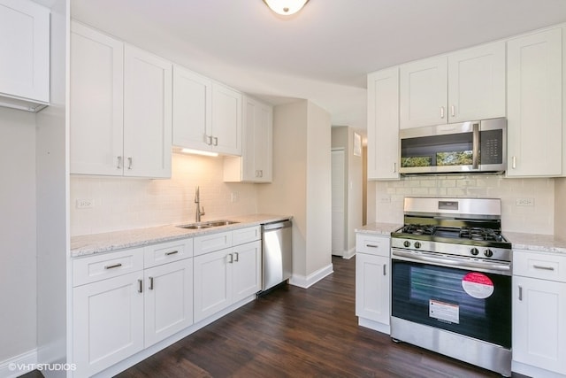 kitchen featuring light stone countertops, appliances with stainless steel finishes, dark hardwood / wood-style flooring, sink, and white cabinetry