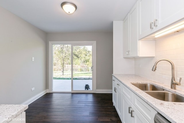 kitchen featuring dark hardwood / wood-style floors, white cabinetry, light stone countertops, and sink