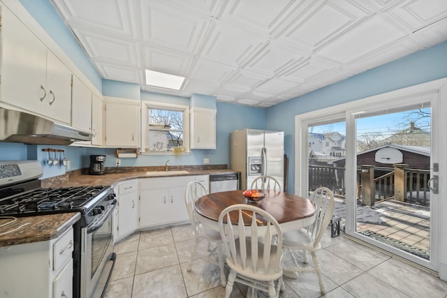 kitchen featuring white cabinetry, sink, dark stone counters, light tile patterned floors, and appliances with stainless steel finishes