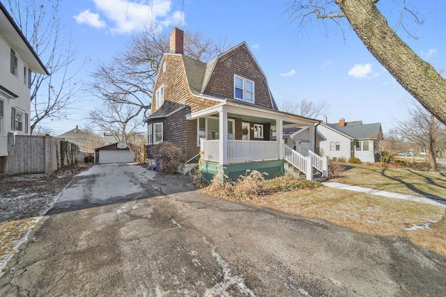 view of front of home with a garage, covered porch, and an outdoor structure