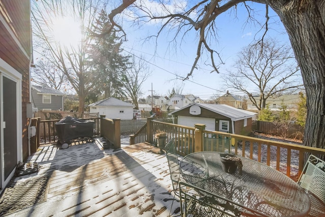 wooden deck featuring a garage, grilling area, and an outdoor structure