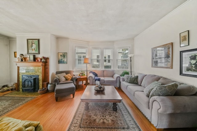 living room featuring crown molding, light wood-type flooring, a wood stove, and a textured ceiling