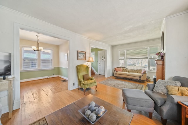 living room featuring a healthy amount of sunlight, light wood-type flooring, and a chandelier