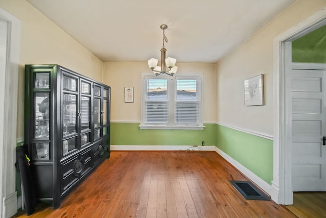 unfurnished dining area with hardwood / wood-style floors and a chandelier