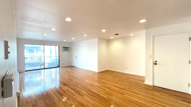 unfurnished room featuring hardwood / wood-style flooring and a wall mounted AC