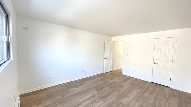 unfurnished bedroom featuring a walk in closet, a closet, and dark hardwood / wood-style floors