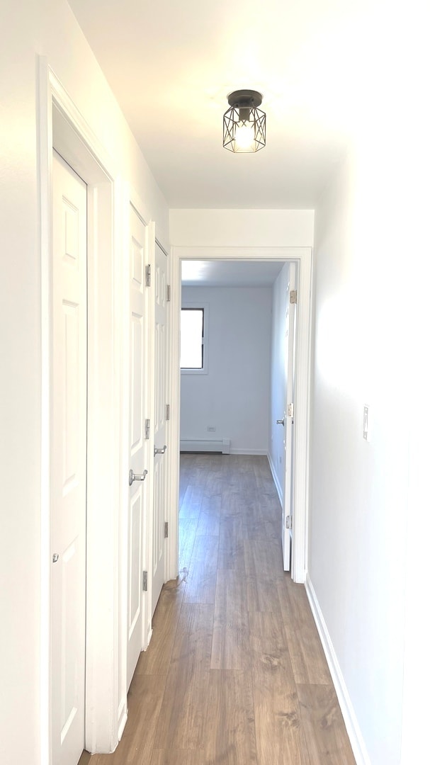 kitchen with sink, white cabinets, stainless steel appliances, and a baseboard heating unit