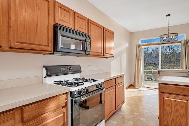 kitchen featuring pendant lighting, range with gas cooktop, a notable chandelier, and sink