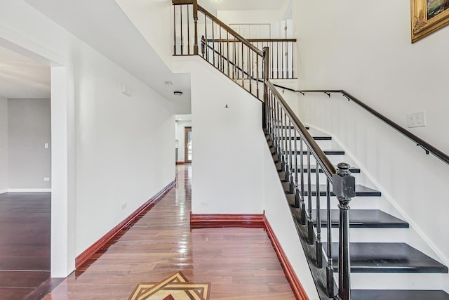 staircase featuring hardwood / wood-style floors and a high ceiling