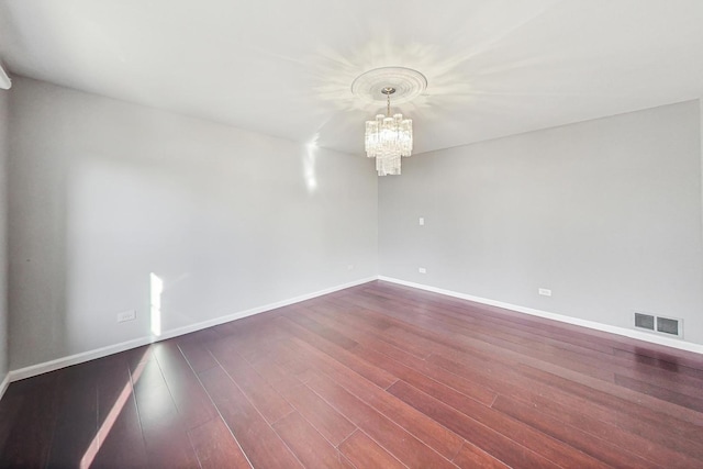 spare room with hardwood / wood-style flooring and an inviting chandelier