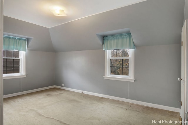 additional living space featuring light colored carpet and vaulted ceiling