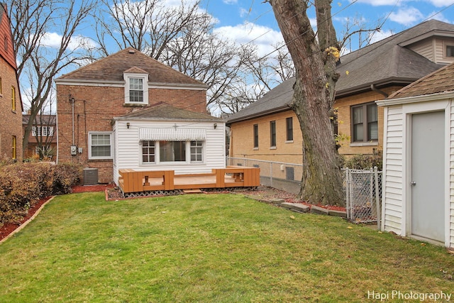 rear view of property with a yard, a wooden deck, and central AC