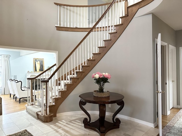 stairway with a towering ceiling, hardwood / wood-style flooring, and plenty of natural light