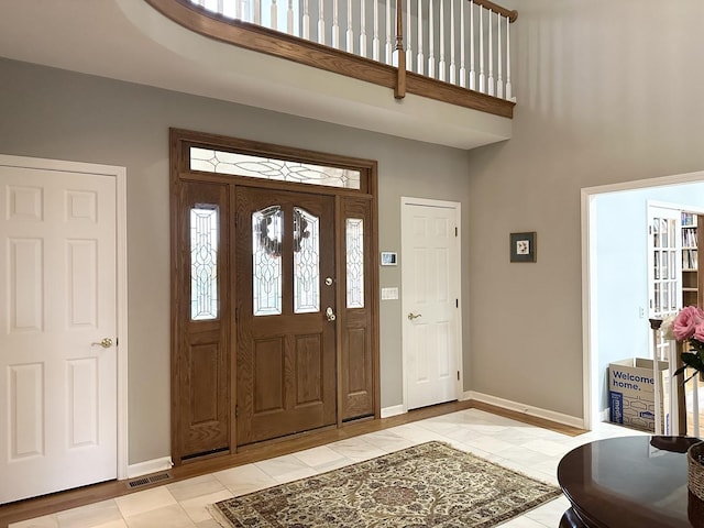 tiled entrance foyer featuring a towering ceiling