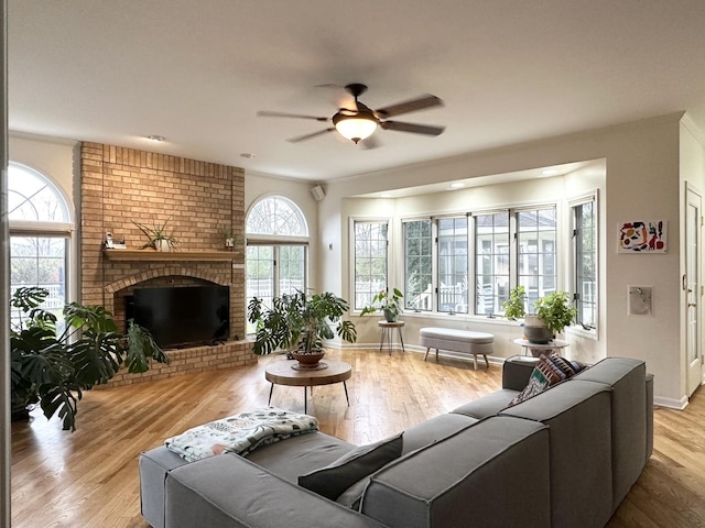 living room featuring ceiling fan, light wood-type flooring, and a fireplace