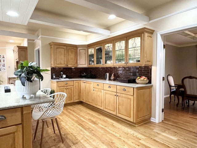 kitchen featuring light stone countertops, light hardwood / wood-style floors, tasteful backsplash, and crown molding