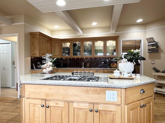 kitchen with tasteful backsplash, stainless steel gas cooktop, beam ceiling, light hardwood / wood-style flooring, and a center island