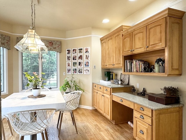 kitchen with pendant lighting, light stone counters, and light wood-type flooring