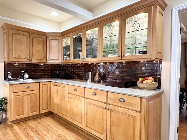 kitchen featuring light stone counters, backsplash, and light hardwood / wood-style flooring