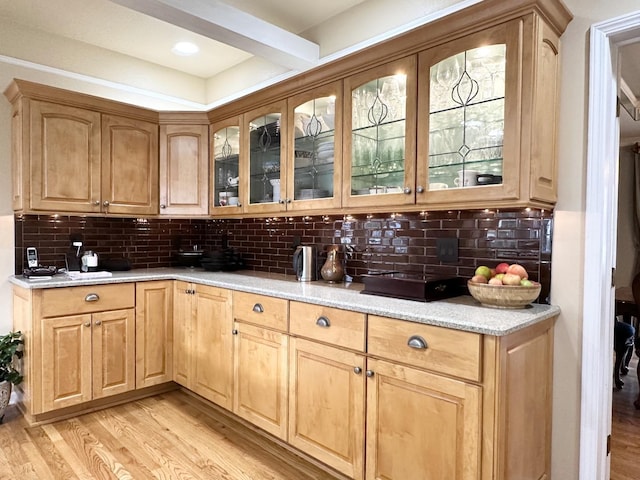 kitchen featuring backsplash, light stone counters, and light hardwood / wood-style floors