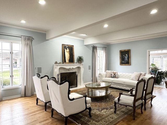 living room featuring crown molding, beamed ceiling, a high end fireplace, and light hardwood / wood-style floors