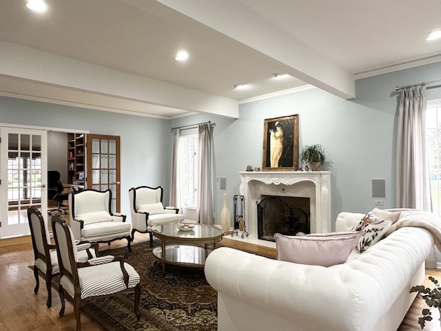 living room with french doors, ornamental molding, hardwood / wood-style flooring, beamed ceiling, and a fireplace