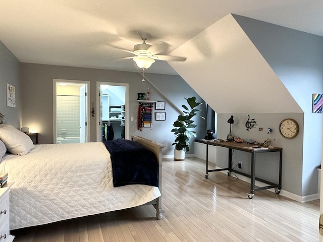 bedroom featuring light hardwood / wood-style flooring, ensuite bath, ceiling fan, and lofted ceiling