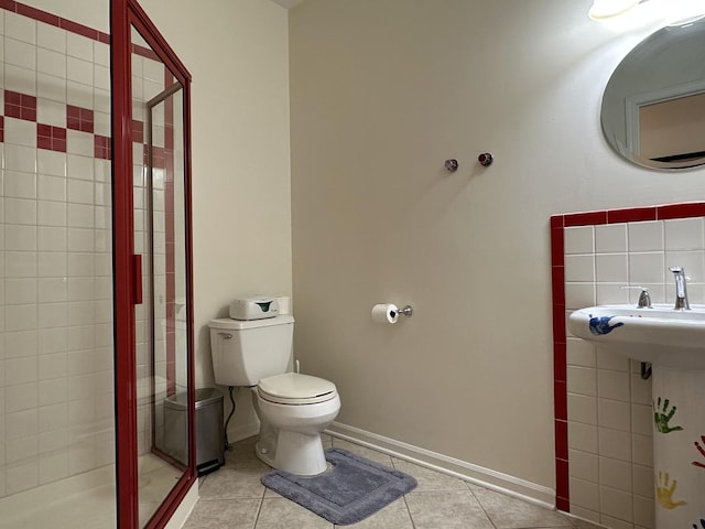 bathroom with tile patterned flooring, a tile shower, and toilet