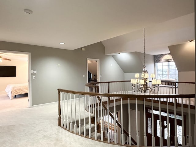 hall featuring carpet floors, a chandelier, and lofted ceiling