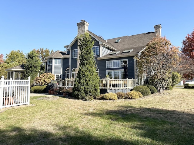 rear view of house featuring a lawn and a deck