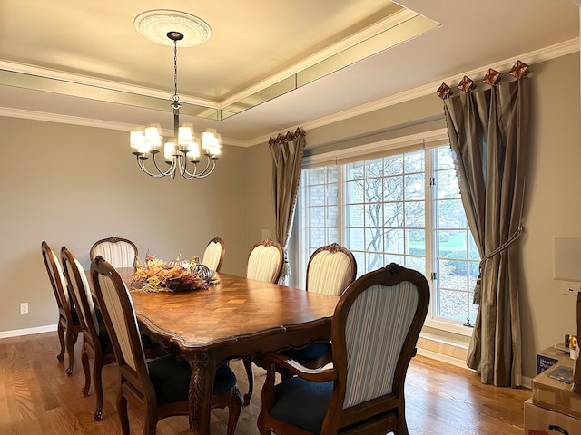 dining room featuring an inviting chandelier, wood-type flooring, ornamental molding, and a tray ceiling