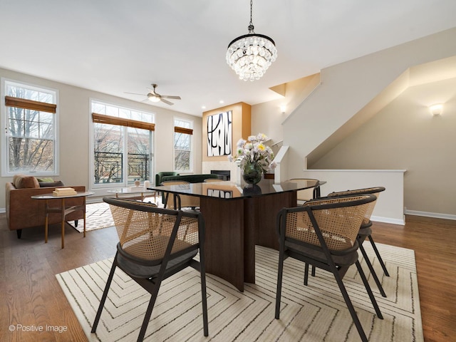 dining area with hardwood / wood-style flooring and ceiling fan with notable chandelier