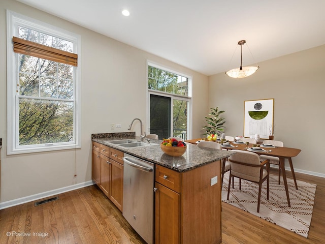 kitchen with dishwasher, sink, light hardwood / wood-style flooring, decorative light fixtures, and kitchen peninsula