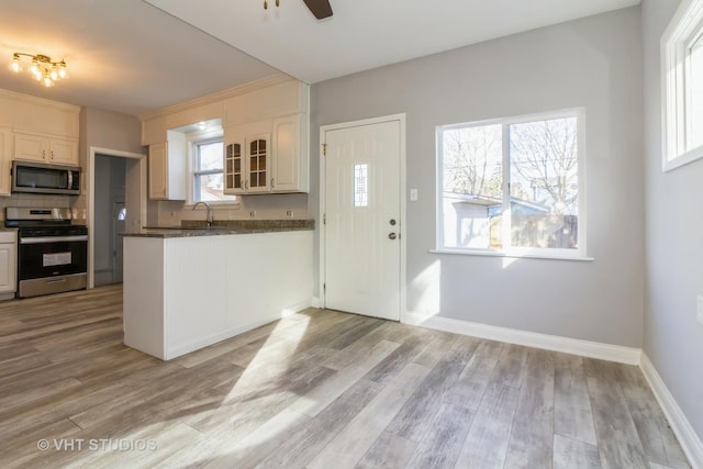 kitchen with stainless steel appliances, white cabinetry, and light hardwood / wood-style floors