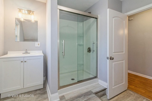 bathroom with hardwood / wood-style floors, vanity, and a shower with shower door