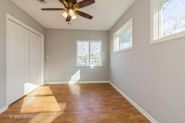 unfurnished bedroom featuring ceiling fan, a closet, and wood-type flooring