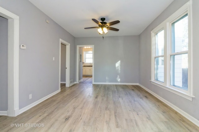 empty room with ceiling fan and light hardwood / wood-style flooring