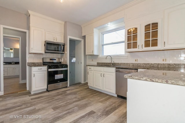 kitchen featuring stainless steel appliances, sink, stone countertops, white cabinets, and light hardwood / wood-style floors