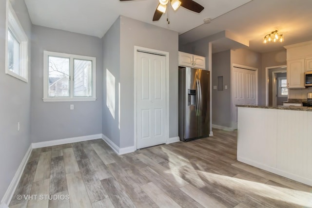 kitchen featuring appliances with stainless steel finishes, dark stone counters, ceiling fan, light hardwood / wood-style floors, and white cabinetry