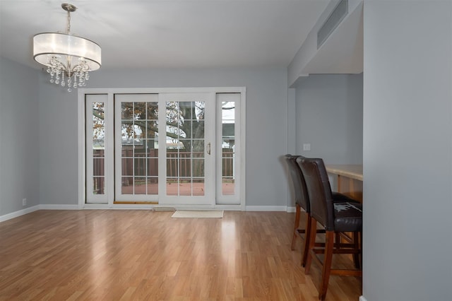 dining space with wood-type flooring and an inviting chandelier