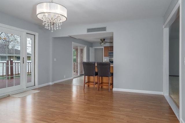 interior space with ceiling fan with notable chandelier and hardwood / wood-style flooring