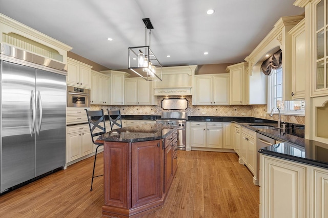 kitchen featuring sink, light hardwood / wood-style floors, pendant lighting, a kitchen island, and high end appliances